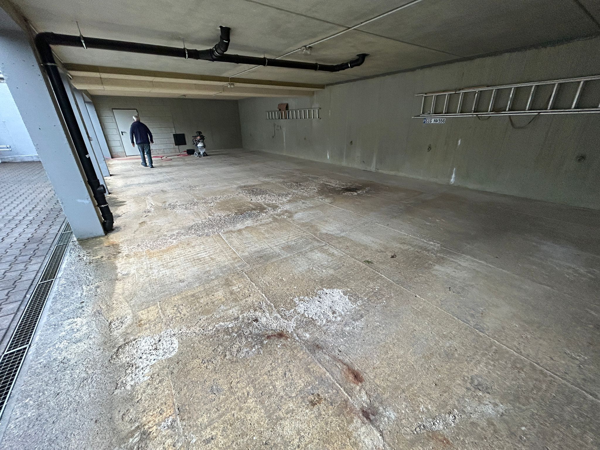Tiefgarage vorher: abgenutzter Betonboden mit Flecken und Abplatzungen
